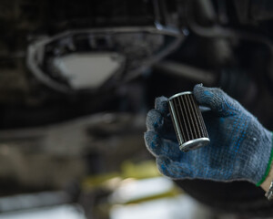 A mechanic replaces the fine filter for the transmission oil. Car on a lift in a car service...