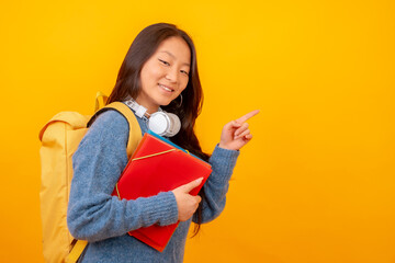 Chinese student with schoolbag and headphones pointing to black space