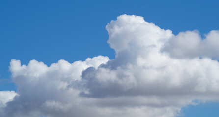 Huge white cumulus clouds against a blue sky.