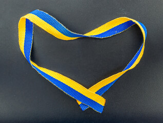 help Ukraine , blue and yellow Ukraine tape in a shape of heart on black background