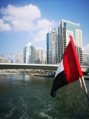 UAE Flag with Modern Dubai Skyline and Waterway

