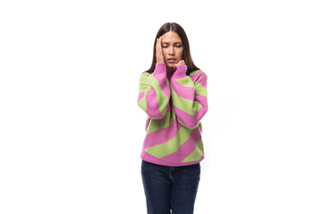 young slender caucasian woman with straight black hair dressed in a striped pink pullover posing on a white background