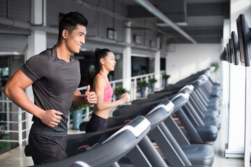 Young couple running on treadmills in gym