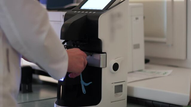 Ophthalmologist measures the refractive power of lenses of kid's glasses on automatic digital lensmeter in private clinic medical center. Modern device gives spherical, cylindrical and axis of lenses