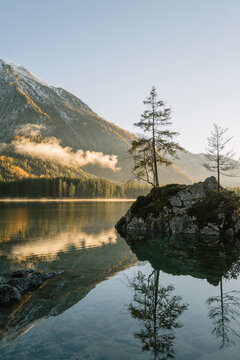 kleine Insel auf dem Hintersee bei Sonnenuntergang mit dem verschneiten Hochkalter im Herbst
