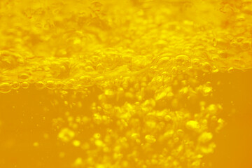 Obraz premium Yellow water with ripples on the surface. Defocus blurred transparent gold colored clear calm water surface texture with splashes and bubbles. Water waves with shining pattern texture background.