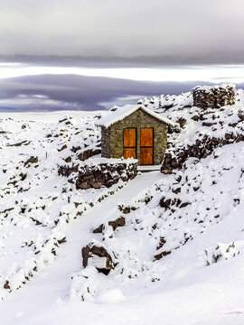 Beautiful, altitude landscape between Arequipa and Chivay, Peru. Andean mountains covered with snow, clouds, morning light. Charming stone house isolated.