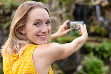 young elegant woman tourist taking photos of landmark