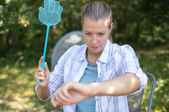 woman on camping holiday tries to catch a mosquito