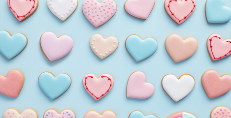 Pattern of colorful heart-shaped homemade cookies sprinkled with colorful confetti on a pastel backdrop. Banner, aerial view, flat layout. Valentine's day and bakery design. Present for holiday