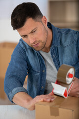 man use tape dispenser to seal a cardboard box