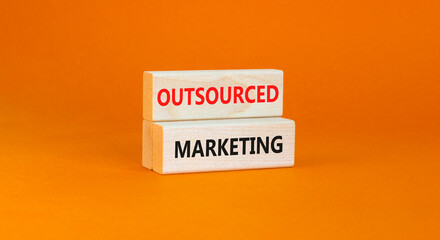 Outsourced marketing symbol. Concept words Outsourced marketing on beautiful wooden blocks. Beautiful orange table orange background. Business Outsourced marketing concept. Copy space.