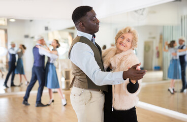 Man and mature woman learning to dance classical ballroom dance