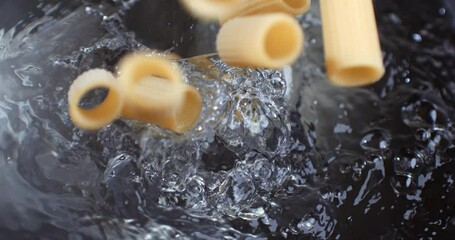 Super slow motion of italian pasta is falling in pot with boiling water to be cooked with traditional recipes for dish preparation by chef in restaurant kitchen. - Powered by Adobe
