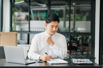 Young handsome man typing on tablet and laptop while sitting at the working wooden table office