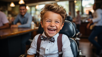 Cute little boy is getting haircut by hairdresser at the barbershop - obrazy, fototapety, plakaty