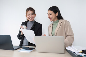 Two Asian businesswomen discuss business planning ideas. Graph analysis on laptop at office