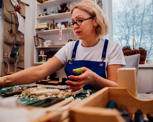 A female carpenter cuts wood with a knife in a carpentry or makeshift workshop. Dust and shavings...