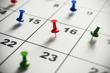 Close-up of a calendar with colorful pins marking important dates. Time management and planning...