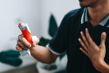 Man having difficulties breathing and using inhaler to relief asthma attack - obrazy, fototapety, plakaty