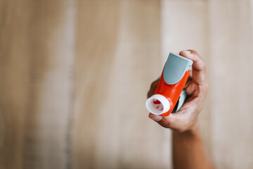 Hand holding plastic spray applicator, used for oral inhalation and prevention of asthma attack