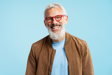 Portrait handsome smiling 50 years old mature man with stylish gray hair wearing red hipster glasses looking at camera isolated on blue background. Vision concept  - obrazy, fototapety, plakaty