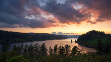 Lake Vyrnwy, located in mid Wales, an area of outstanding natural beauty, at sunset. The orange sky is reflected in the calm water of the lake