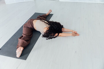 Beautiful sporty curly woman doing yoga asana fitness exercises on the floor