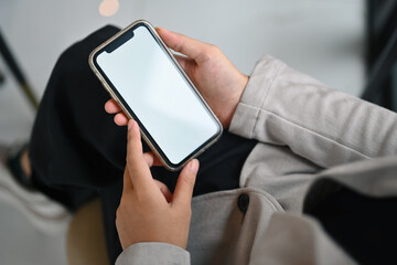 Closeup female worker holding mobile phone with white empty screen