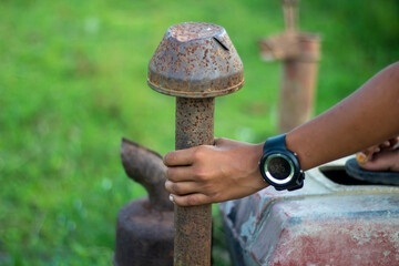 A man is holding an engine silencer with his hand and a blurred background