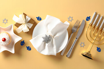 Hanukkah tableware, cutlery, gift boxes, menorah, jelly donut on golden table. Jewish holiday...