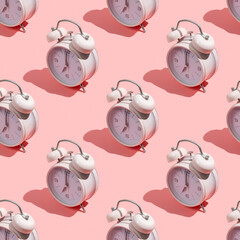 Seamless pattern with alarm clock on pink background.