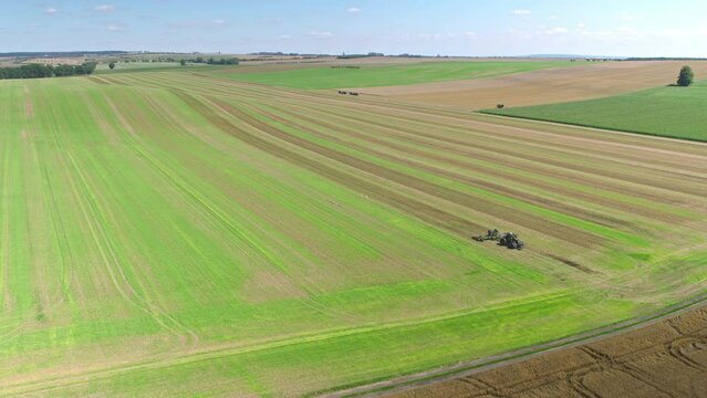 Machines till the fields for the coming harvest year. Wide angle drone shot.