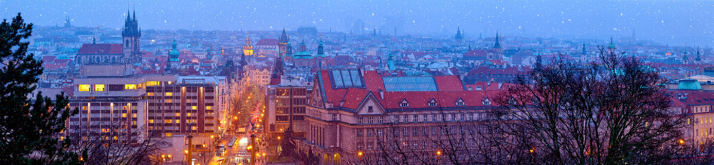 Naklejka premium Prague Czech Republic. Wide panorama. Panoramic view at nighttime winter old town with falling snow, towers of prague. Illuminated street aerial Christmas time during seasonal holidays.