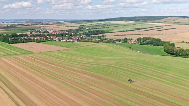 Machines till the fields for the coming harvest year. Wide angle drone shot.