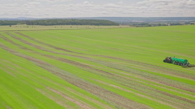 Machines till the fields for the coming harvest year. Wide angle drone shot.