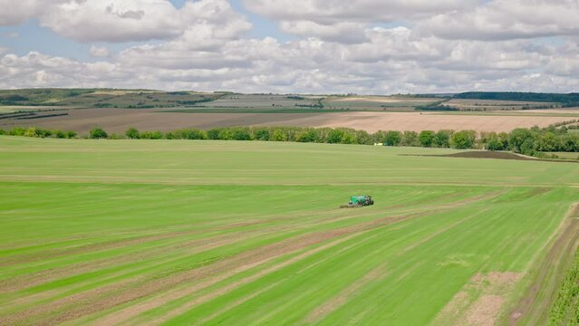 Machines till the fields for the coming harvest year. Wide angle drone shot.