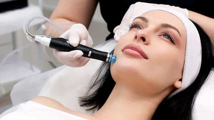 Cosmetology clinic. Professional female cosmetologist doing hydrafacial procedure while being a...