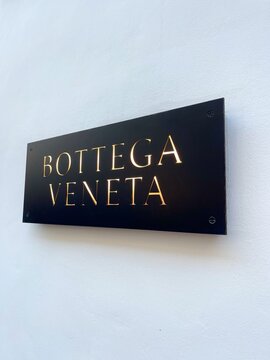 Brand Bottega Veneta sign on the wall close-up view. Name plate Italian luxury fashion house. Famous worldwide trademark. Bottega Veneta is headquartered in Milan, Italy. Part of Kering luxury group. 