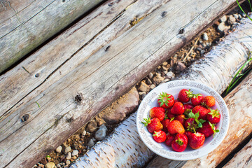 Close-up strawberry crop lying in a plate on rural wooden steps. The concept of healthy food, vitamins, agriculture, market, strawberry sale