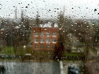Rainy day in the industrial city. View through wet window with raindrops moment seeing industrial area during rain storm. Background.