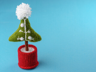 handmade knitted Christmas tree on a blue background, copy space.