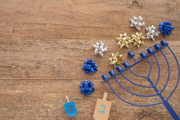 Obraz premium Menorah, wooden dreidels for Jewish holiday Hanukkah on wooden background with copy space. Hebrew letters on dreidels say: 