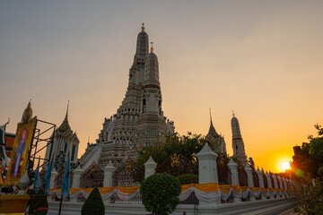 Fototapeta premium scenery sunset behind the large illuminated temple Wat Arun the biggest and tallest pagoda in the world beside Chaophraya river Bangkok, Thailand..pagoda in golden sunset popular landmark in Bangkok