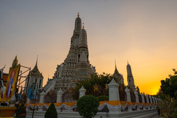 Fototapeta premium scenery sunset behind the large illuminated temple Wat Arun the biggest and tallest pagoda in the world beside Chaophraya river Bangkok, Thailand..pagoda in golden sunset popular landmark in Bangkok
