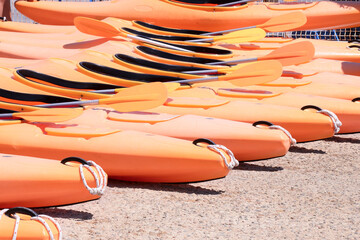 group of waterproof dinghy kayaks lined up in the color of the year apricot crash. Sports boats on...