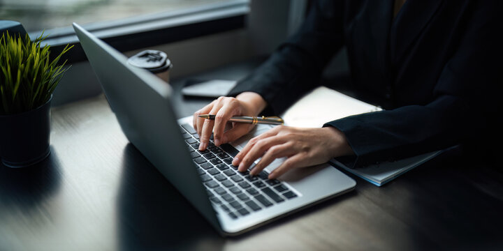 Close up Asian business woman using laptop to calculate tax and financial data of business at office