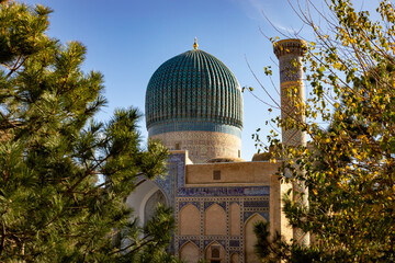 Obraz premium tree covering the both side and the middle part with a beautiful historical building with a beautiful Dome on the top, Amir Temur Mausoleum, madrasah, Samarkand, autumn.