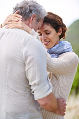 Fototapeta premium Couple, face and smile in nature with hug for romance, love and relationship outdoor with date. Mature, man and woman or embrace with happy, marriage and joyful for bonding, honeymoon and support