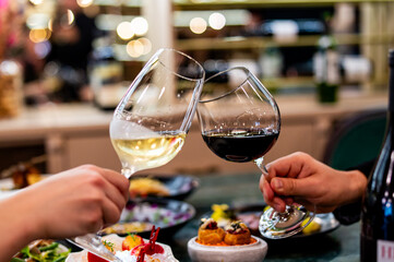 hands young couple man and woman clinking with glasses of red and white wine at restaurant